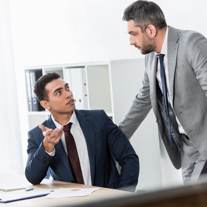 serious professional businessmen talking and looking at each other in office